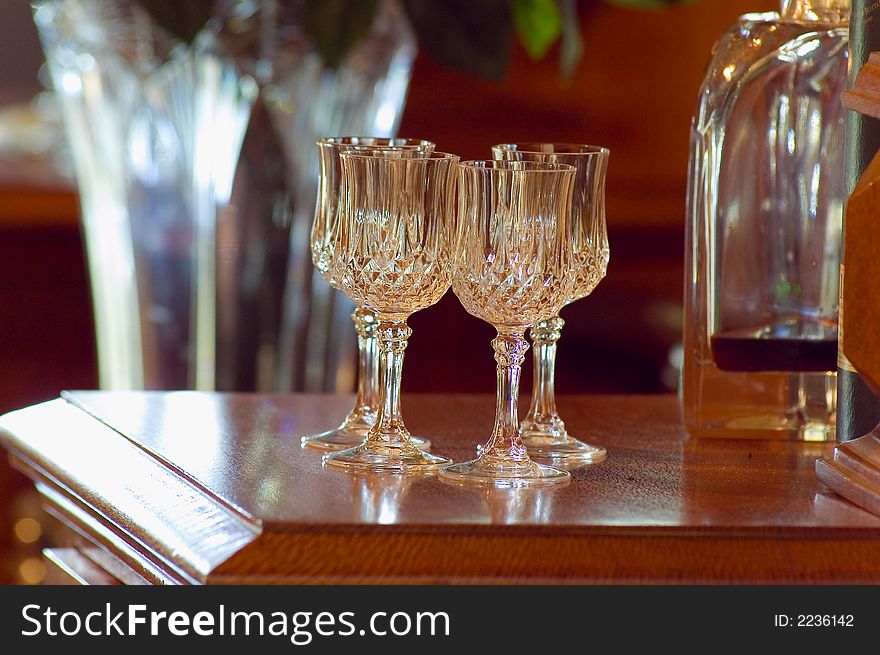 Crylstal glasses standing on  wooden cabinet in a formal lounge room. Crylstal glasses standing on  wooden cabinet in a formal lounge room