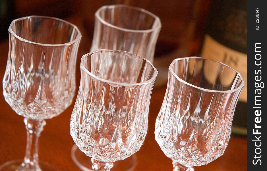 Crystal glasses displayed next to a bottle of scotch in a formal lounge room