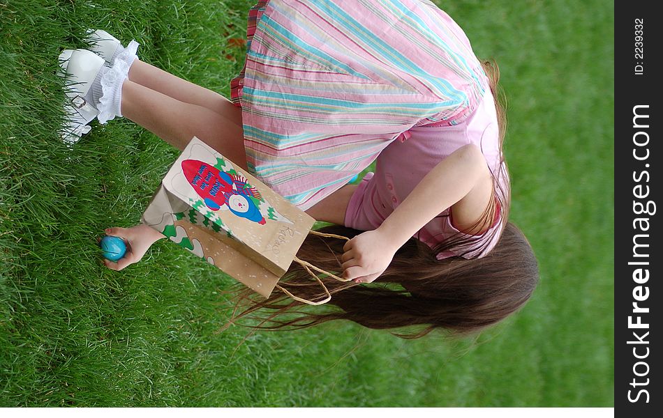 Little girl retrieving an easter egg into her bag. Little girl retrieving an easter egg into her bag.