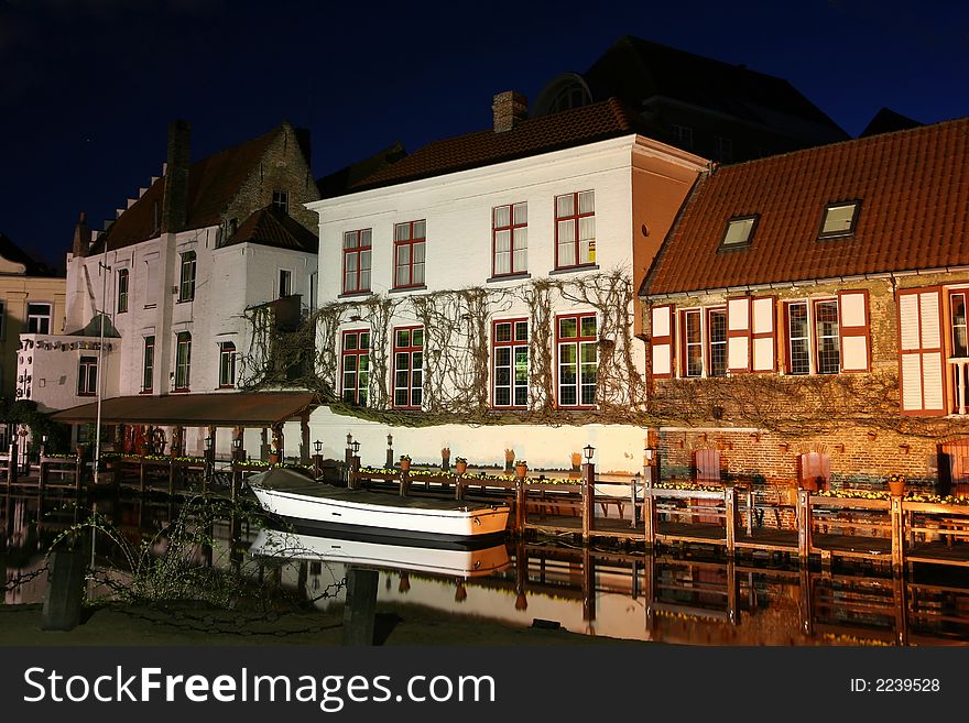 Bruges (Belgium) by night. A small boat near a row of old houses. Bruges (Belgium) by night. A small boat near a row of old houses