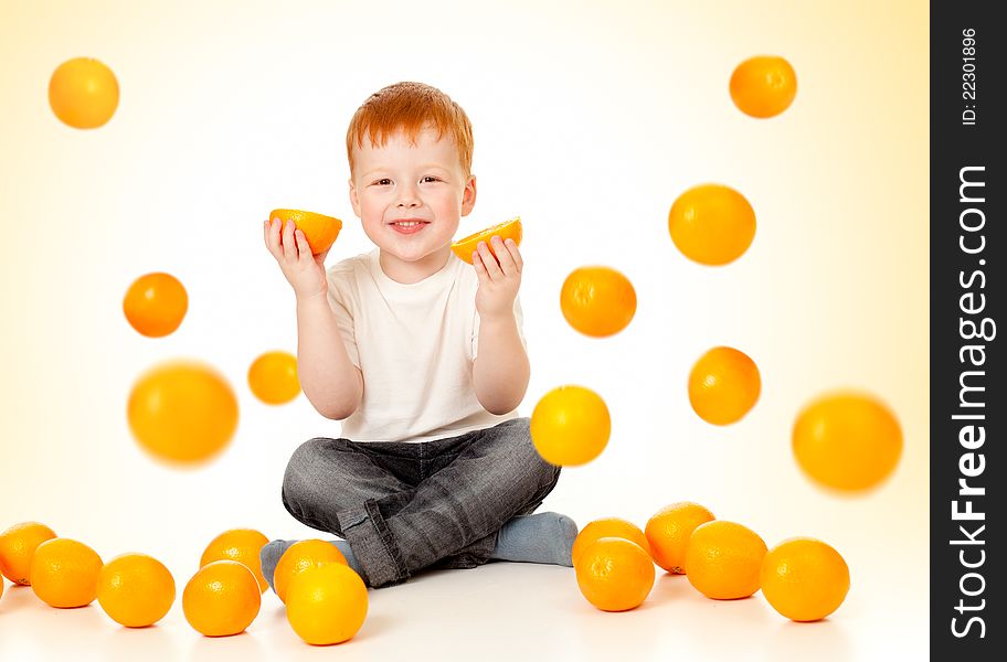 Redheaded boy in studio with falling oranges and oranges in his hands. Redheaded boy in studio with falling oranges and oranges in his hands