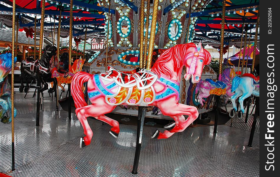 Pink carousel horse on colorful merry-go-round