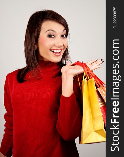 A beautiful young brunette girl smiling happily. Bee hand bags with Christmas and New Year shopping. A beautiful young brunette girl smiling happily. Bee hand bags with Christmas and New Year shopping.