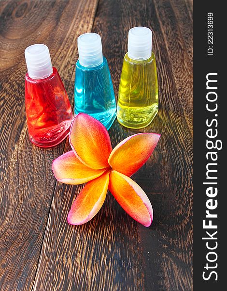 Toiletries and plumeria flower on wood floor