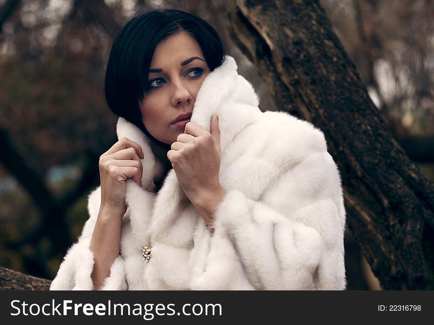 Elegant girl with black hair in white coat with high collar. Elegant girl with black hair in white coat with high collar