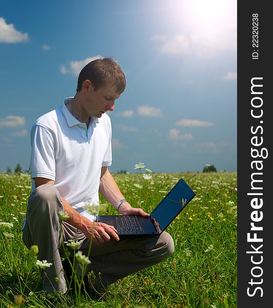 Mobile man working on notebook in the meadow
