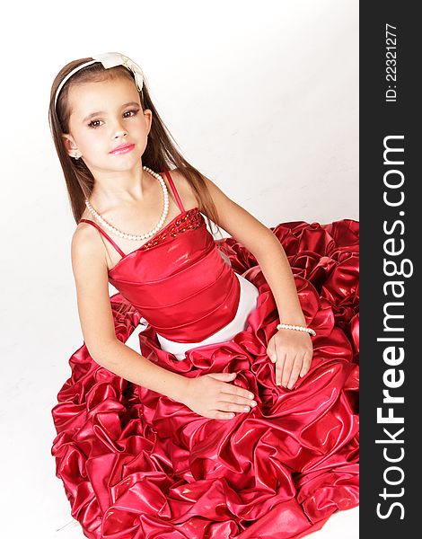 Beautiful little girl in red evening dress on white background
