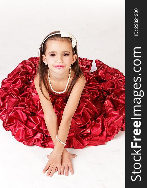 Beautiful little girl in red evening dress on white background