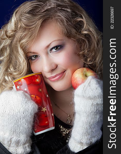 Girl with a long fair hair in knitted mittens and an apple in hands. Girl with a long fair hair in knitted mittens and an apple in hands