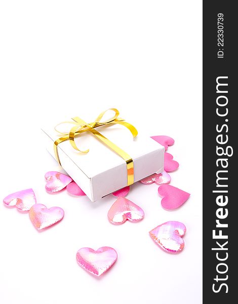 White gift box with gold ribbon decorate pink heart shape spread on screen. White gift box with gold ribbon decorate pink heart shape spread on screen.