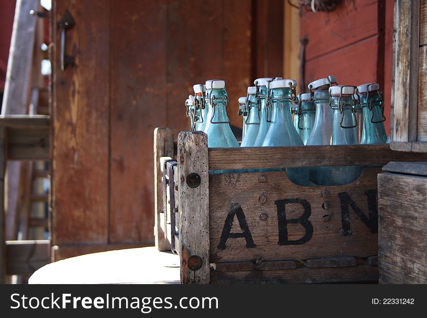 A boundle of bottles in a box outside a ol house