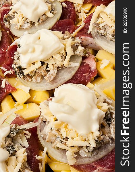 Raw meat on potato with cheese onion and mushrooms