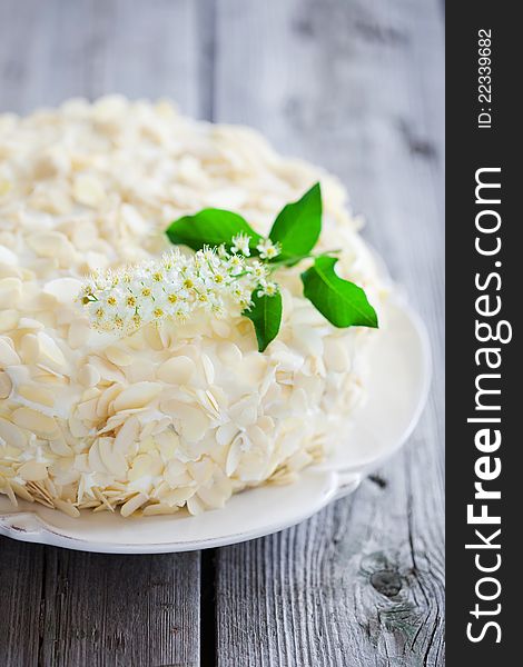 Bird cherry cake with almonds and whipped cream, decorated with bird cherry flowers, selective focus