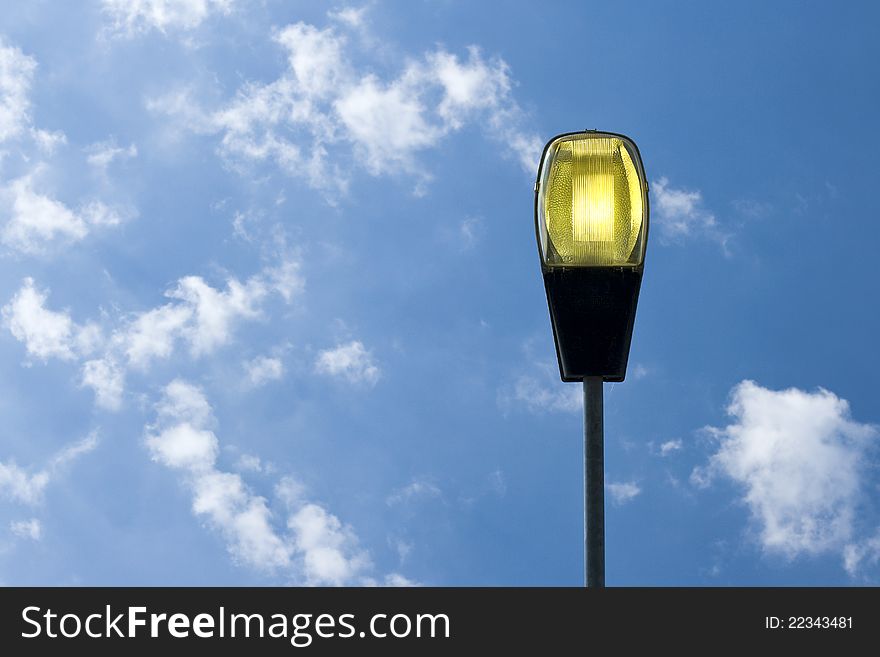 Light on, streetlamp against blue sky. Light on, streetlamp against blue sky.