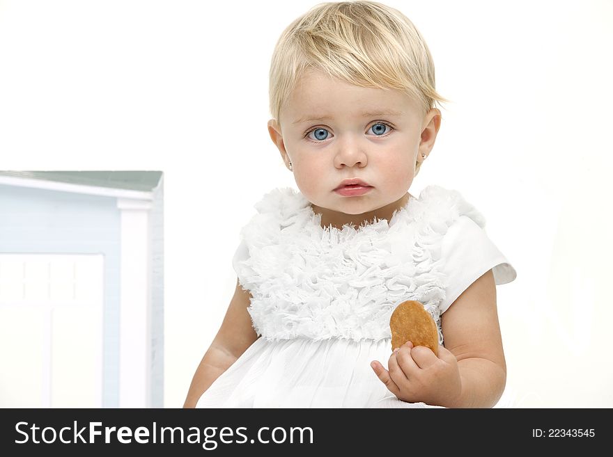 Blue eyed baby girl with boring expression holding a biscuit. Isolated on white background. Blue eyed baby girl with boring expression holding a biscuit. Isolated on white background.