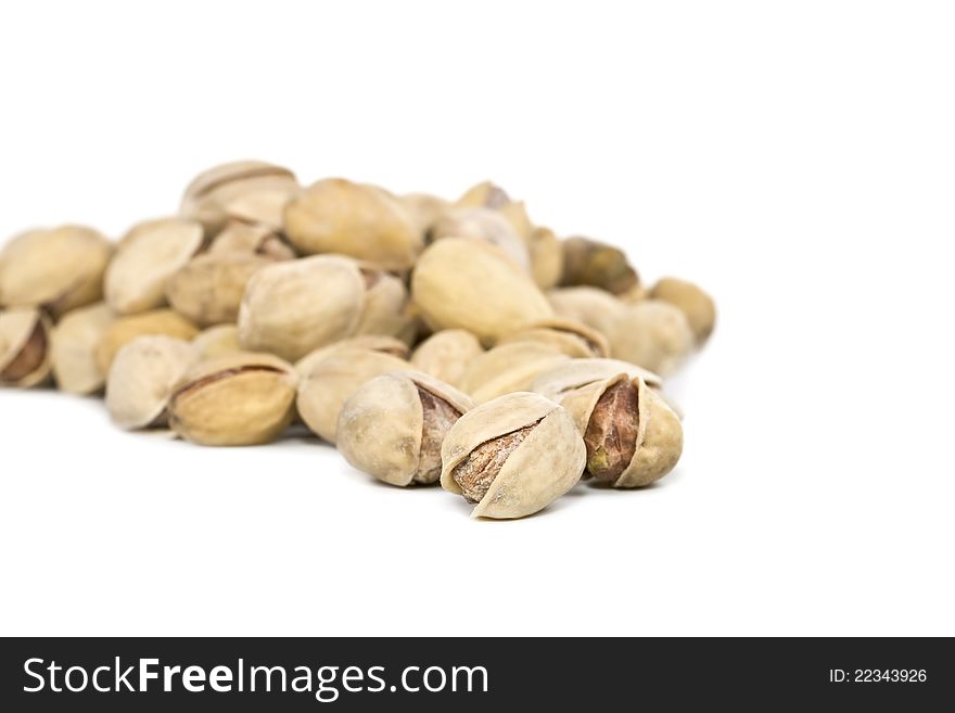 Salted pistachios are scattered on a white background, the focus is on the first plan. Salted pistachios are scattered on a white background, the focus is on the first plan.
