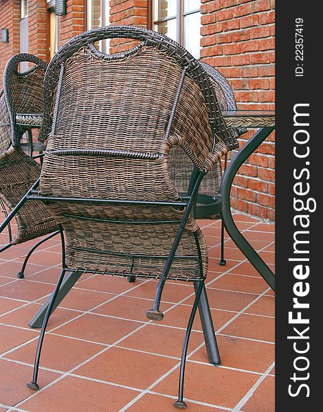 Folded wicker chairs and a table in a street cafe. Folded wicker chairs and a table in a street cafe