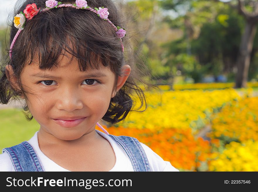 Little asian girl smile with shallow focus on flowers background. Little asian girl smile with shallow focus on flowers background