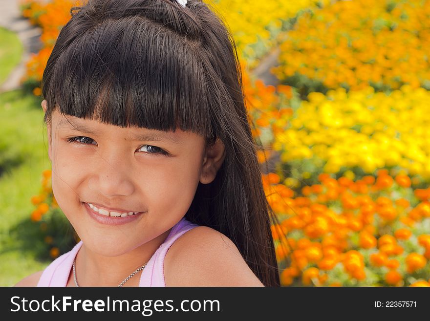 Little asian girl smile with shallow focus on flowers background. Little asian girl smile with shallow focus on flowers background