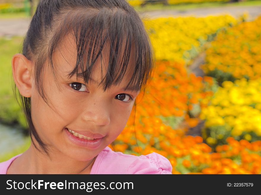 Little asian girl smile with shallow focus on flowers background. Little asian girl smile with shallow focus on flowers background