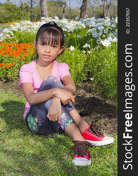 Little asian girl smile with shallow focus on flowers background. Little asian girl smile with shallow focus on flowers background