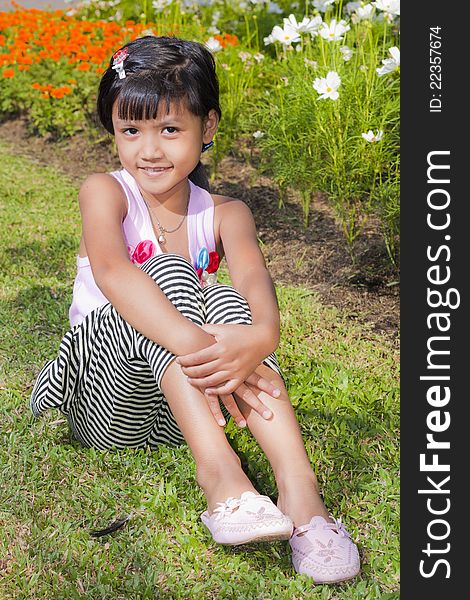 Little asian girl smile with shallow focus on flowers background. Little asian girl smile with shallow focus on flowers background