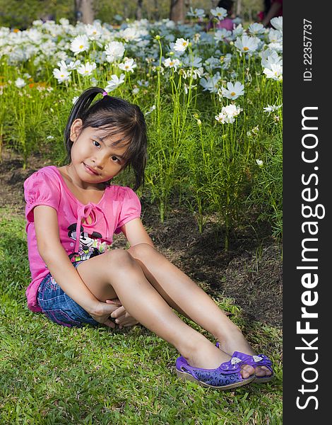 Little asian girl smile with shallow focus on flowers background. Little asian girl smile with shallow focus on flowers background