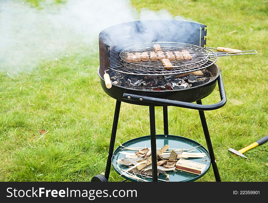 Outdoor scenery of grilling meat, with big smoke.