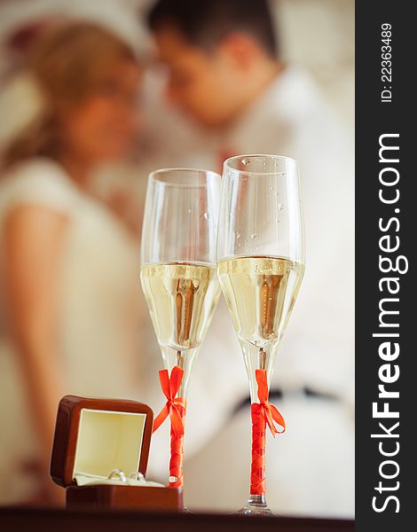 Wedding champagne glasses and newly weds as the background