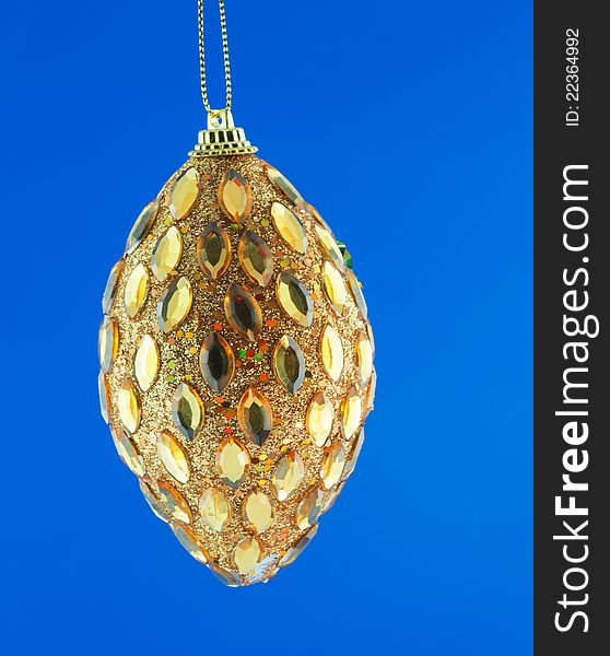 Gold cone, Christmas decorations hanging on a golden thread against the blue background. Gold cone, Christmas decorations hanging on a golden thread against the blue background