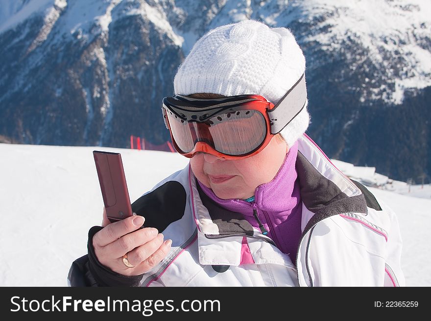 Skier in the mountains with a mobile phone in his hand