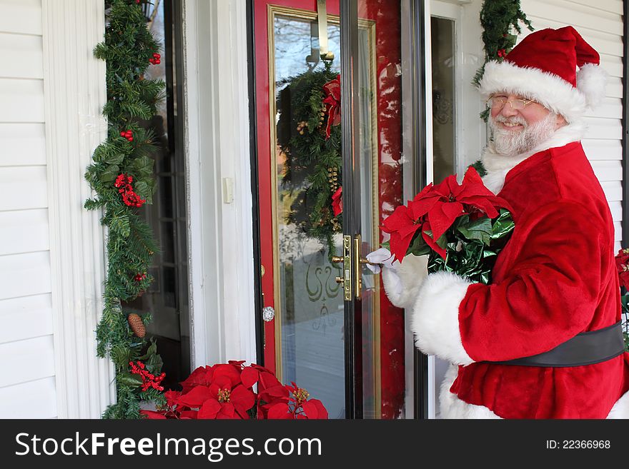Santa Claus in front of a door decorated for Christmas. Santa Claus in front of a door decorated for Christmas.