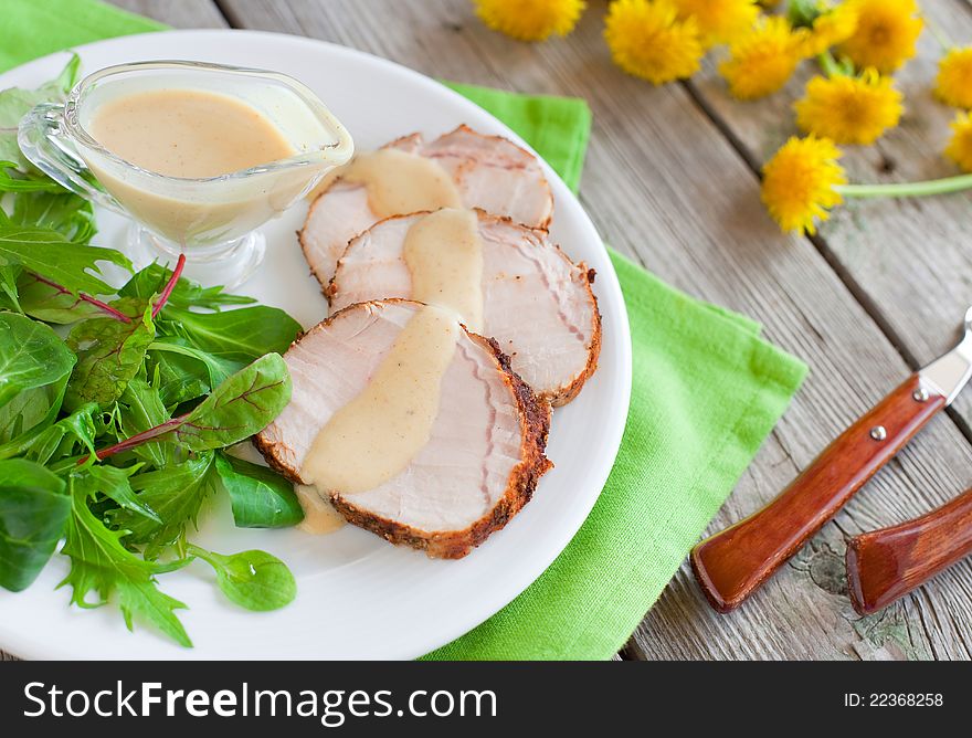 Roasted pork slices with apple and curry sauce and green salad on the plate