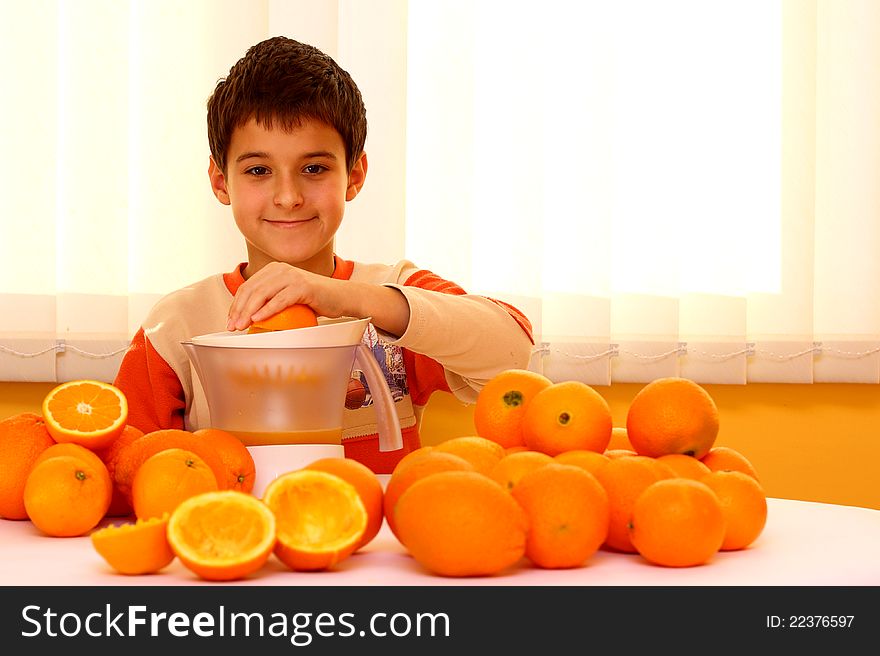 A boy making ( press out ) fresh orange juice surrounded with many oranges. A boy making ( press out ) fresh orange juice surrounded with many oranges