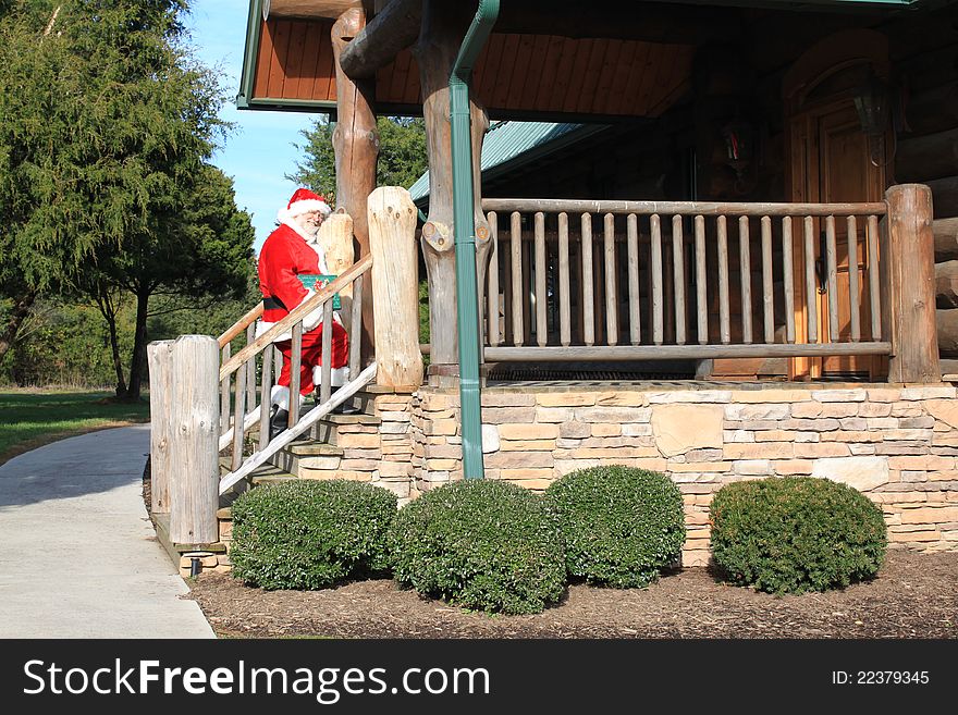 Santa Claus going up the stairs to deliver a gift to the residents of this log cabin home. Santa Claus going up the stairs to deliver a gift to the residents of this log cabin home.