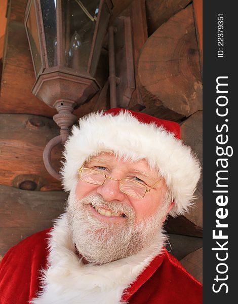 Santa Claus in front of a log cabin with an antique looking lantern above his head. Santa Claus in front of a log cabin with an antique looking lantern above his head.