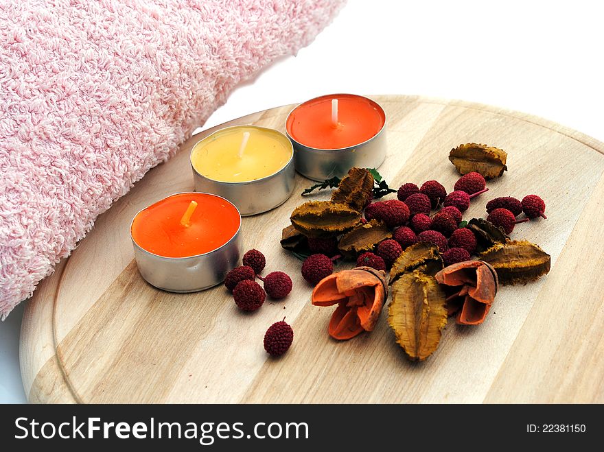 Three candles with dried flowers in wooden dish