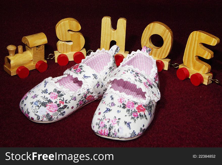 Baby shoes for a little girl with wooden toy train in the background. Baby shoes for a little girl with wooden toy train in the background