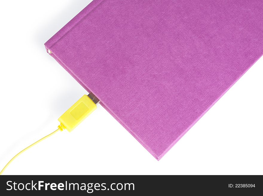 A violet-coloured closed book with a yellow cable connector leading in to the pages, isolated on white The concept idea. The paper book with USB as ebook. A violet-coloured closed book with a yellow cable connector leading in to the pages, isolated on white The concept idea. The paper book with USB as ebook.