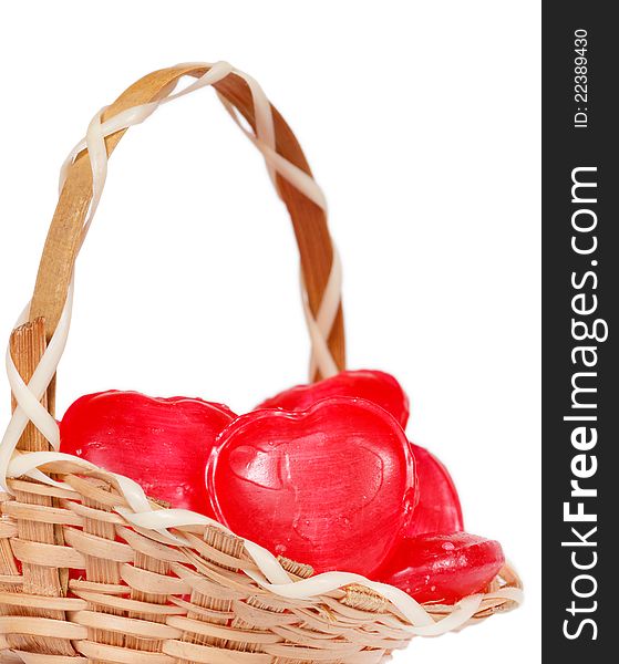 Tiny little wicker basket full of heart shape candy isolated on white background