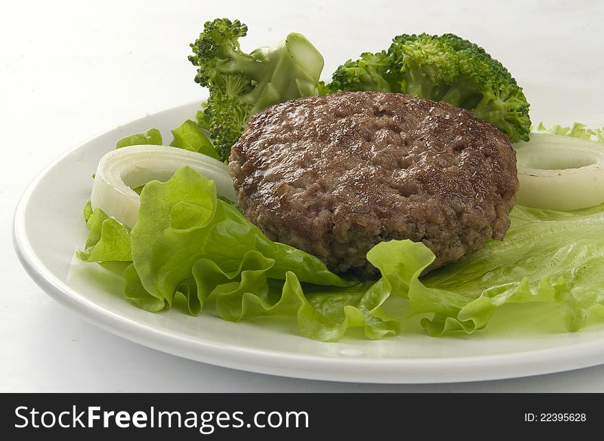 Meat rissole with broccoli, lettuce and onion on the plate