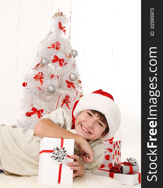 Cheerful child with Christmas gifts and a Christmas tree on a white background