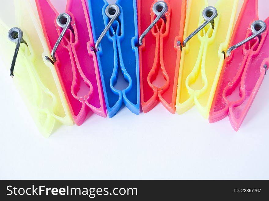 Colored clothes pegs in sequence on white background