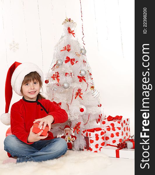 Little girl with a Christmas gift sitting beside Christmas tree. Little girl with a Christmas gift sitting beside Christmas tree