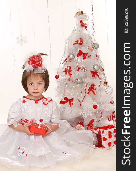 Little girl with a Christmas gift sitting beside Christmas tree. Little girl with a Christmas gift sitting beside Christmas tree