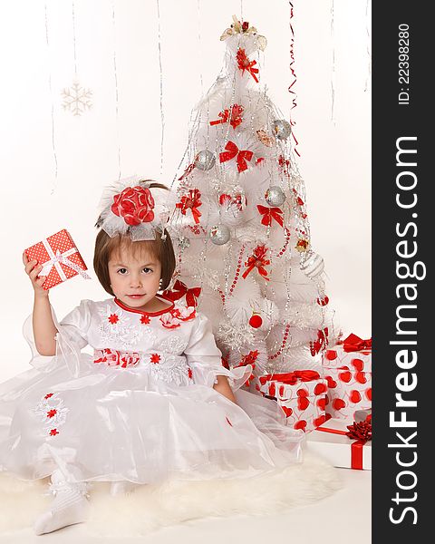 Little girl with a Christmas gift sitting beside Christmas tree. Little girl with a Christmas gift sitting beside Christmas tree