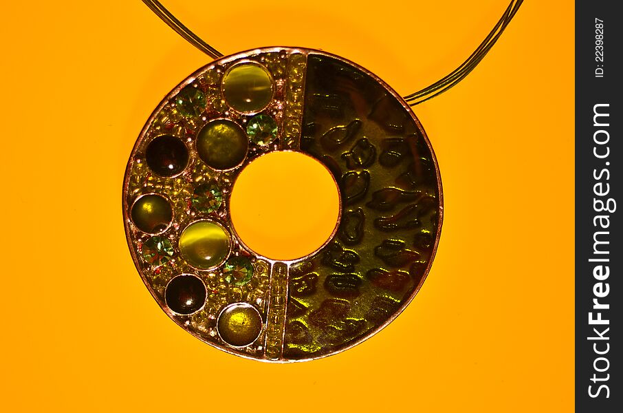 Pendant with green stones on yellow background.