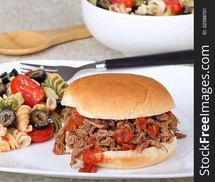 Italian beef on a bun with pasta salad. Italian beef on a bun with pasta salad