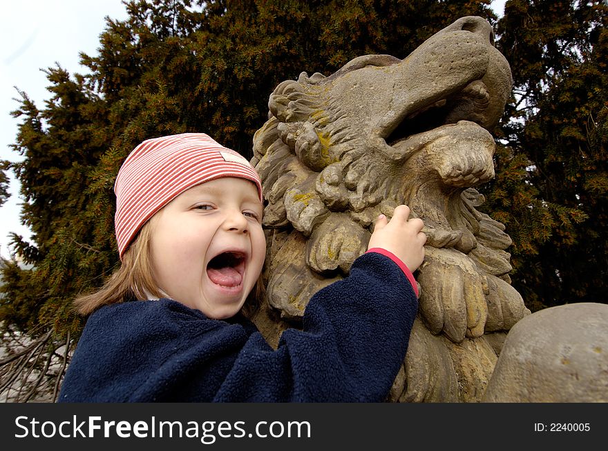 Little girl scream with laughter at the sculpture of lion. Little girl scream with laughter at the sculpture of lion