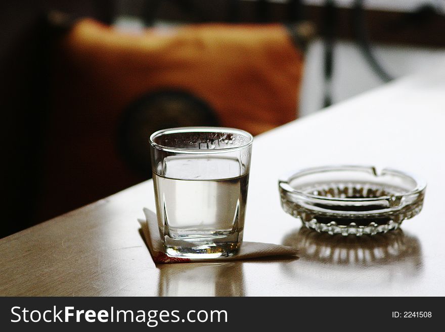 Glass and ashtray on table